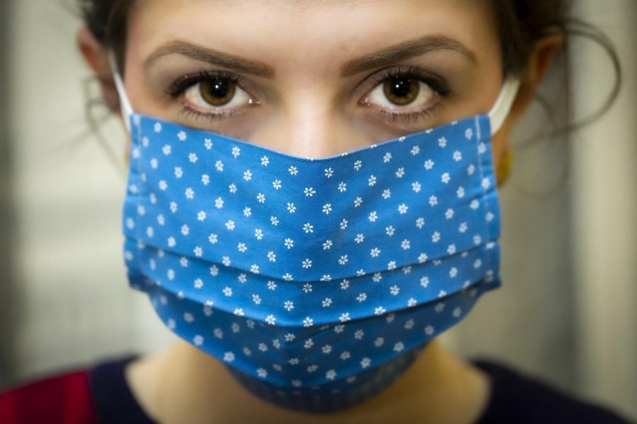 A+woman+wears+a+cloth+mask+to+help+prevent+the+spread+of+the+novel+coronavirus.+Infection+rates+are+down%2C+but+we+must+continue+taking+precautions+until+the+virus+no+longer+poses+a+major+threat+to+our+population.+