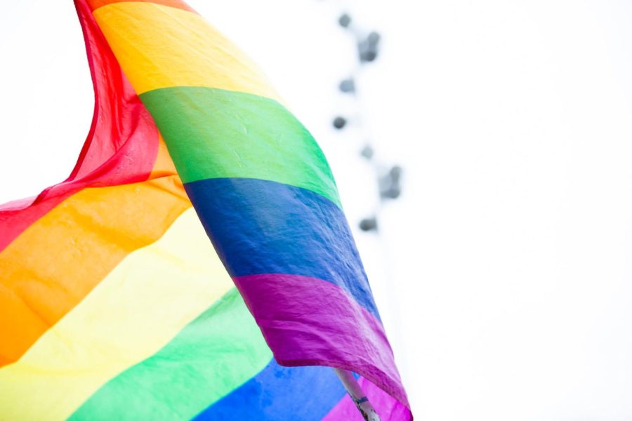LGBTQ+ rainbow flag flies over a clear background.